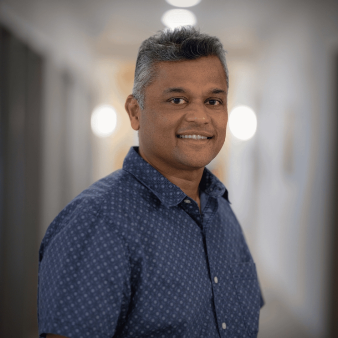 Smiling man with graying hair in a blue shirt, embodying Mined XAI's vision for transparent, human-in-the-loop enterprise AI.