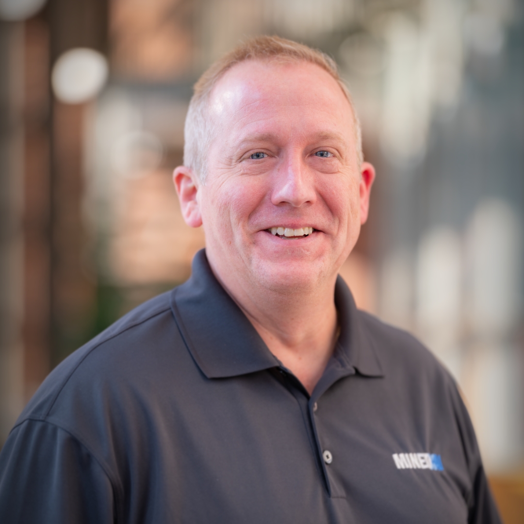 Smiling Mined XAI professional in a grey polo shirt, embodying explainable AI and human-in-the-loop intelligence.