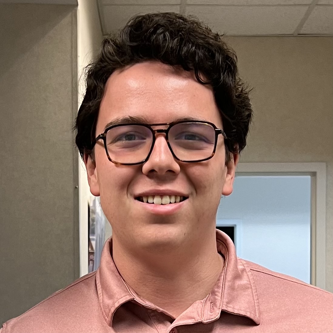 Smiling young man in glasses, embodying human-centered intelligence for explainable AI solutions at Mined XAI.